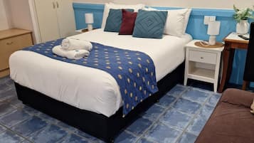 A neatly made bed with a blue and white duvet, a blue and white patterned throw, and a pair of towels.