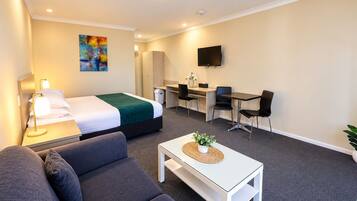 A hotel room with a bed, a desk, a TV, a sofa, and a coffee table.