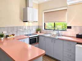 Cozinha moderna com forno embutido, micro-ondas e janela com vista para vegetação.