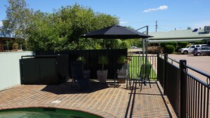 Un patio con piscina, mobiliario exterior y una zona de estar cubierta.