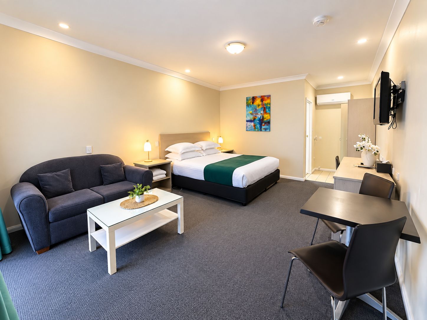 Una habitación de hotel con una cama, un sofá, una mesa de comedor y una silla.