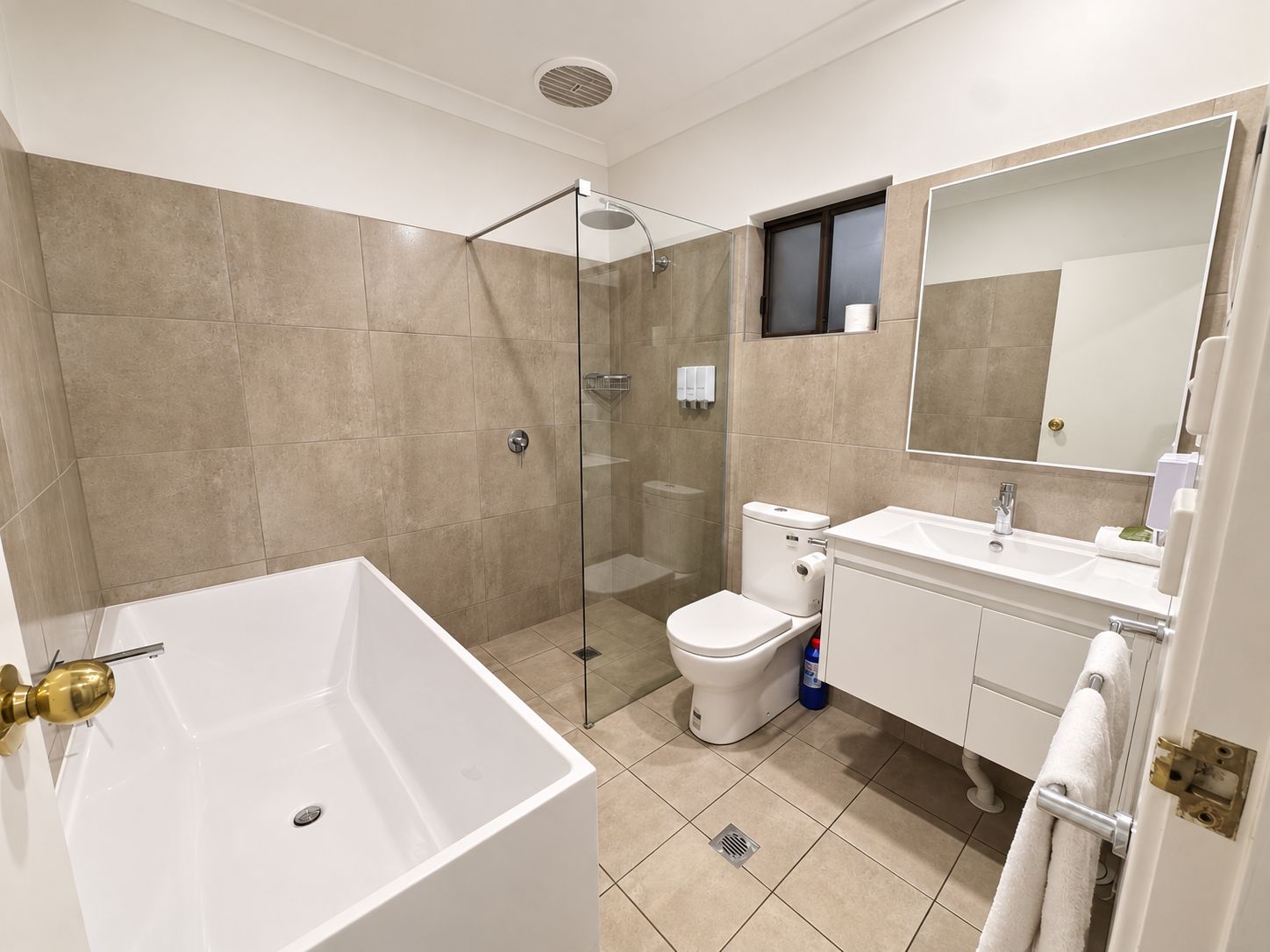 A modern bathroom with a glass-enclosed shower, a white bathtub, and a toilet.