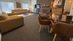 Una sala moderna con sofá, mesa de centro y mesa de comedor con cubierta de vidrio y sillas.