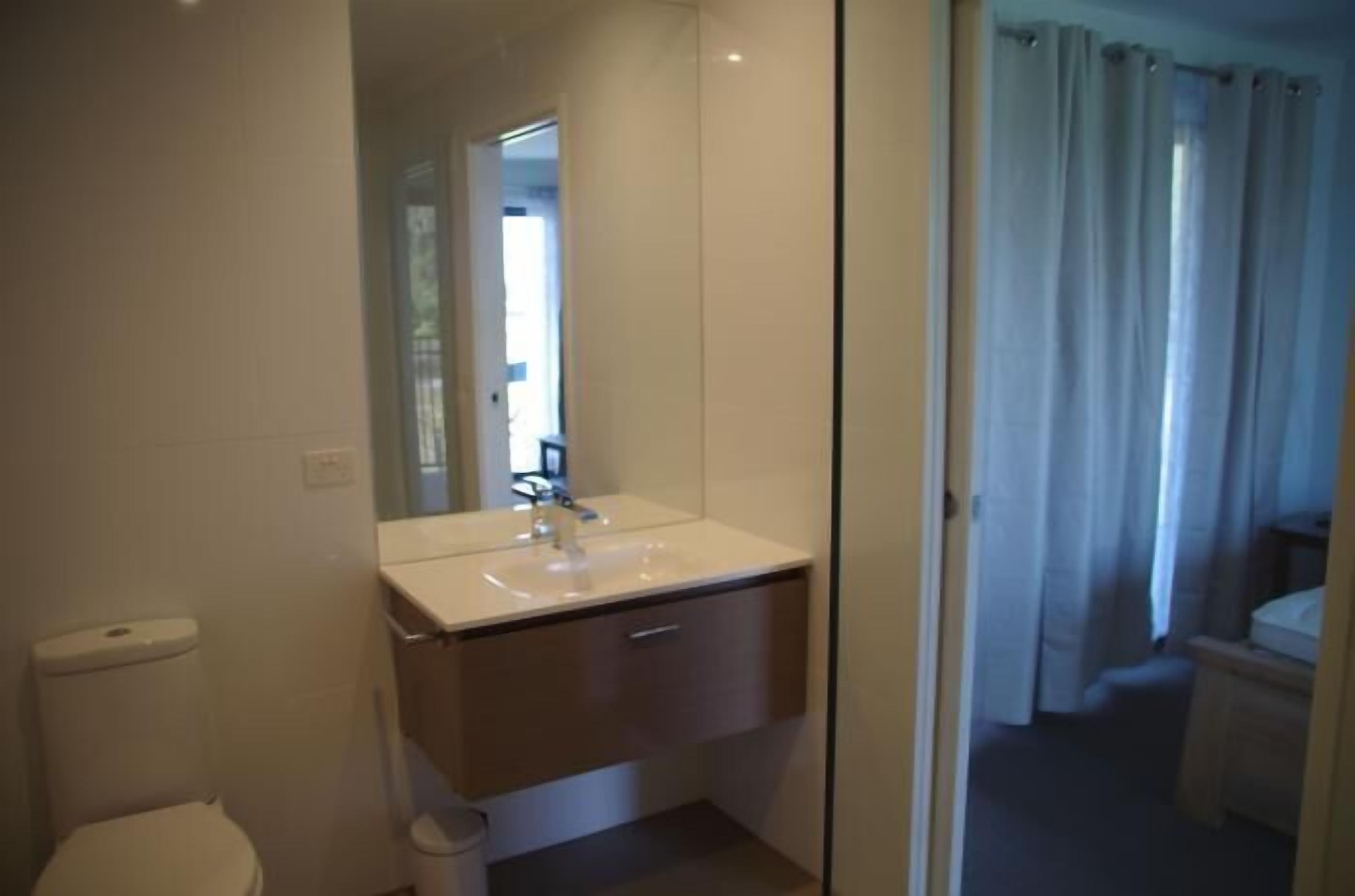 Une salle de bain moderne avec un lavabo blanc, un miroir et des toilettes.