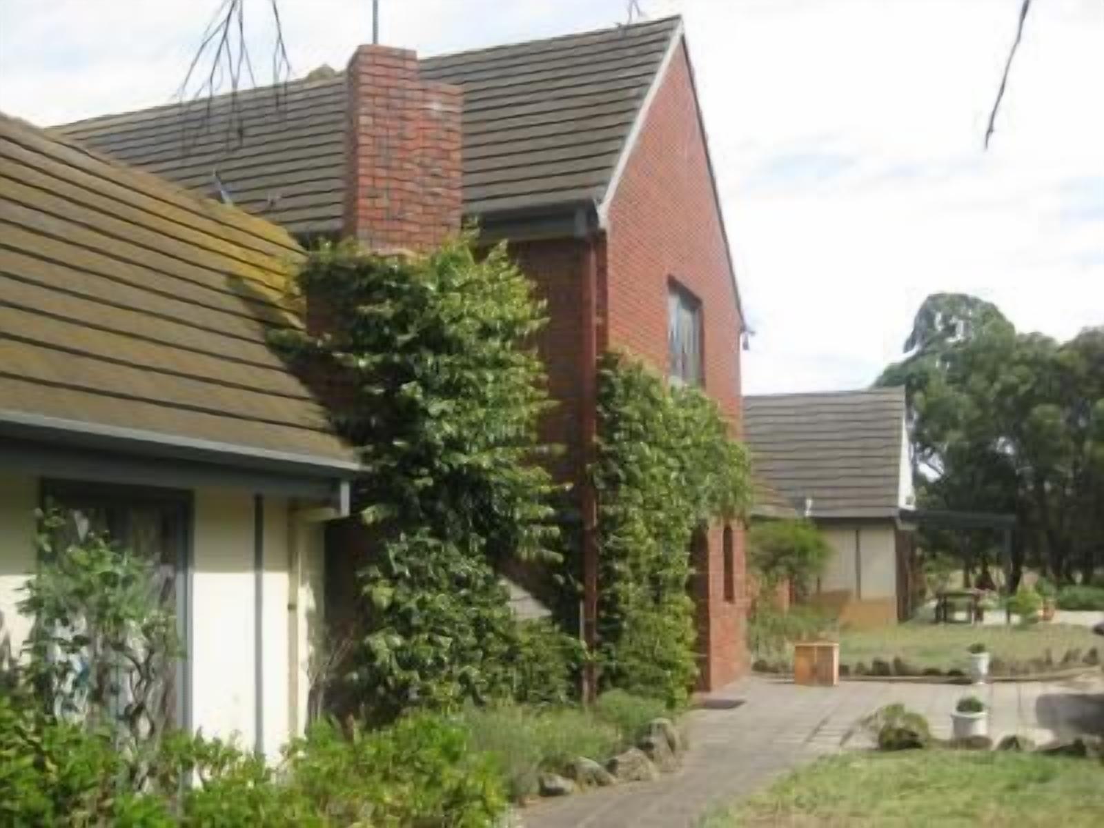 A residential building with a brick chimney, a wooden roof, and a garden with a pathway.