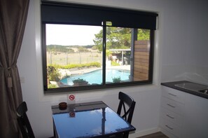 Une pièce avec vue sur une piscine, une table à manger et un coin cuisine.