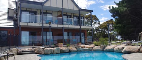 Una piscina al aire libre, sillones reclinables de piscina