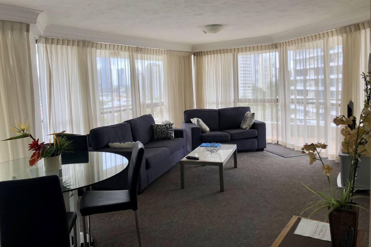A modern living room with a sofa, a coffee table, and a dining area with chairs.