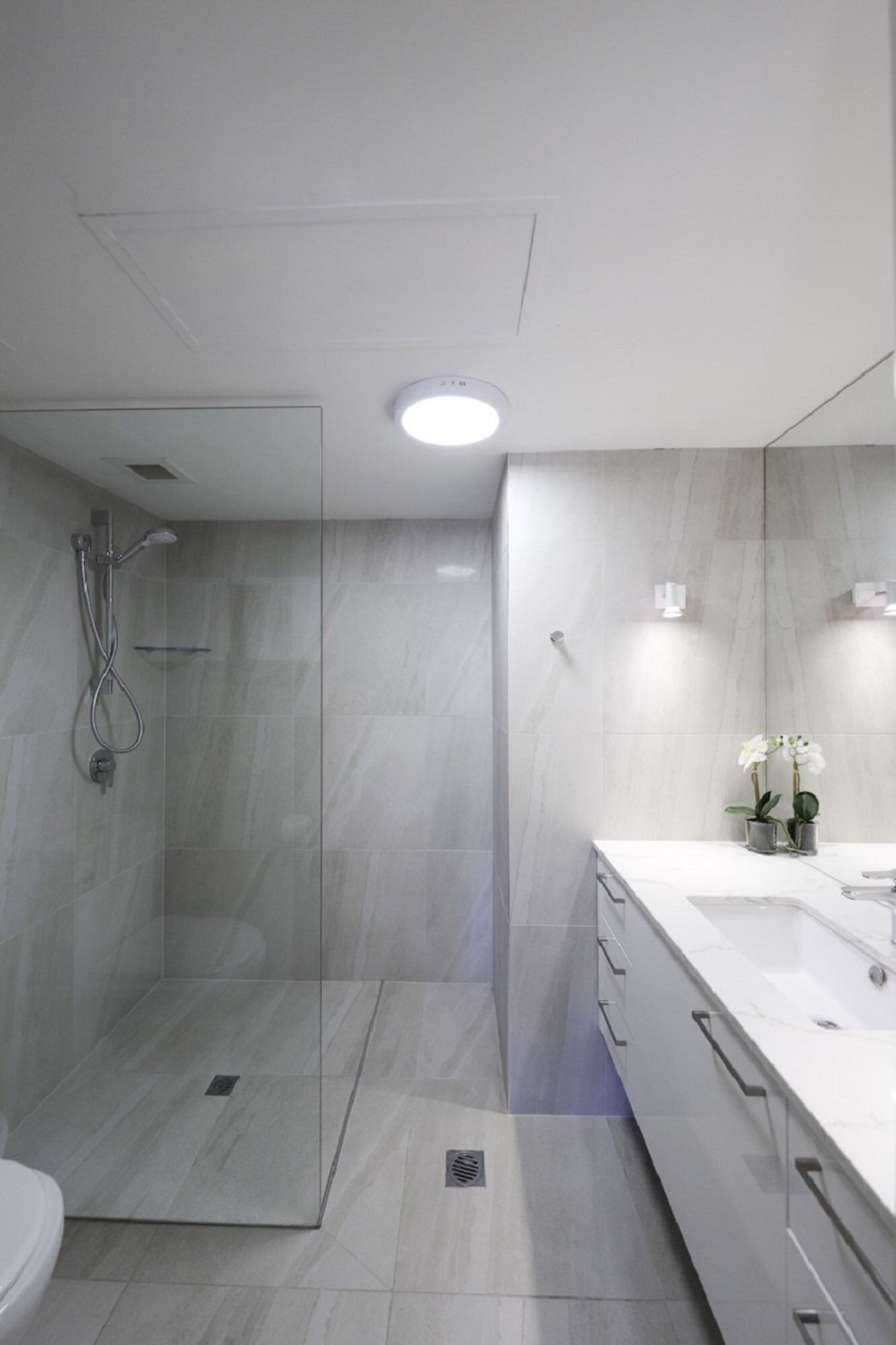 A modern bathroom with a glass-enclosed shower, a white sink, and a mirror.