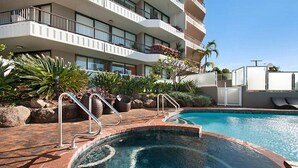A hotel with a swimming pool, outdoor plants, and a multi-story building with balconies. - Bougainvillea Luxury Apartments (Main Beach)