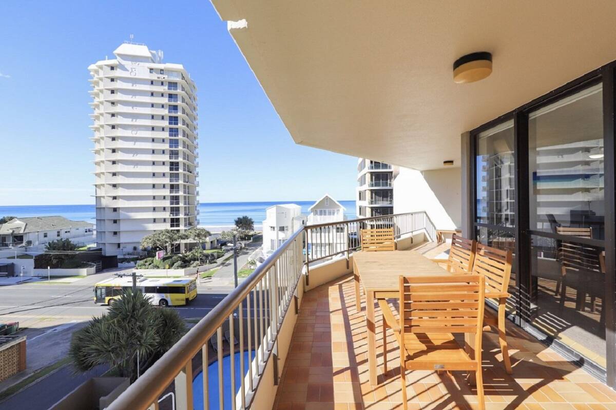 A balcony with a view of the sea and a tall building.