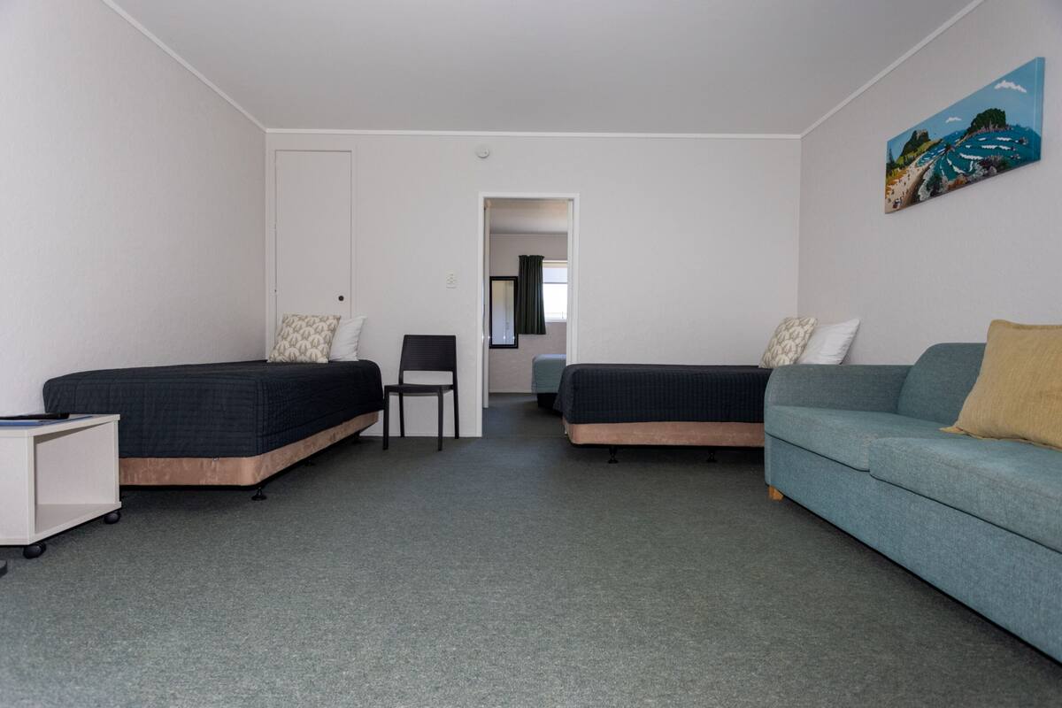 A room with two single beds, a sofa, a desk, and a chair.