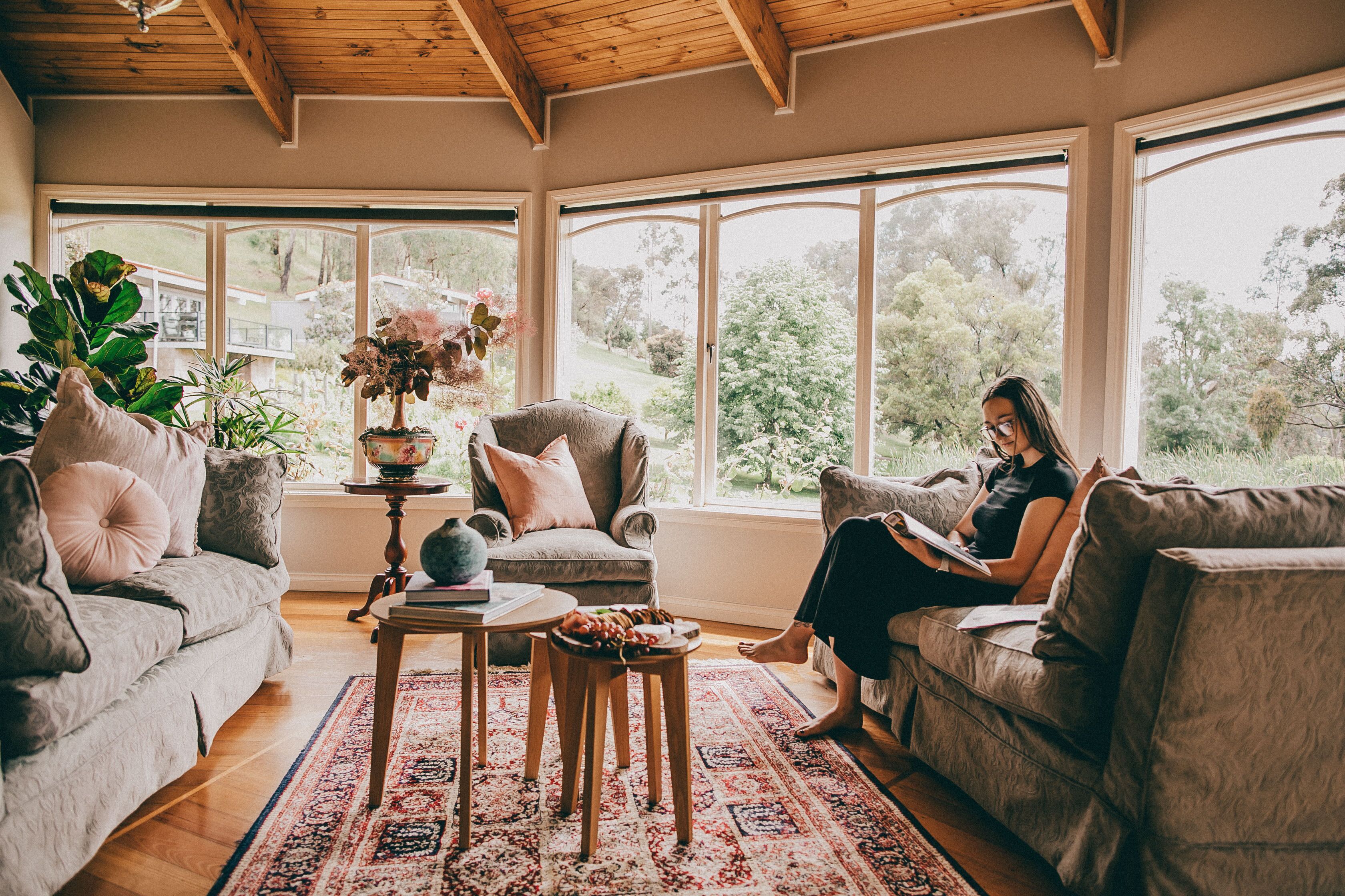 A cozy living room with a large window, a sofa, a chair, and a coffee table.