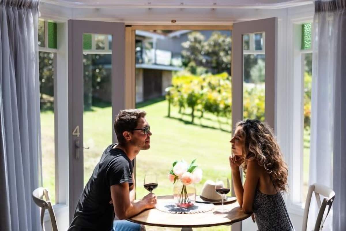 Ein Paar speist an einem Tisch mit Blick auf einen Garten und ein Haus im Hintergrund.