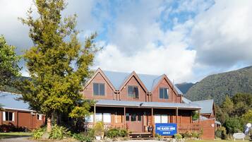 A lodge with a wooden exterior, a porch, and a sign indicating it is the Fox Glacier Lodge.