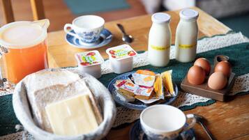 Una mesa de desayuno con tostadas, mantequilla, huevos, leche y una taza de café.