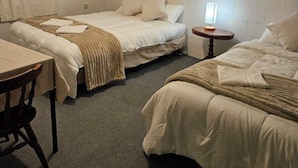 Una habitación con tres camas, una mesa y una lámpara.