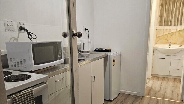 Cocina compacta con microondas, hervidor y refrigerador pequeño.