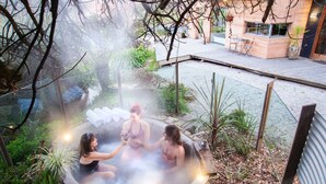 A hot spring with three people sitting in it surrounded by greenery. - Dreamers (Tawonga South)