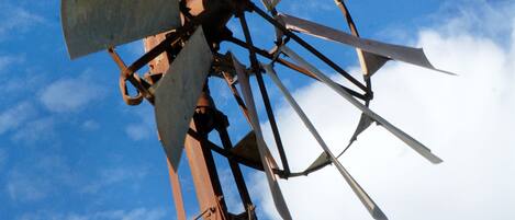 A windmill with multiple blades against a blue sky with clouds.