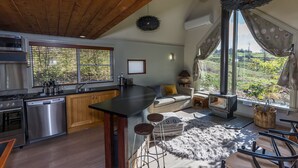 A modern kitchen with a large island, stainless steel appliances, and a cozy seating area with a fireplace. - Dreamers (Tawonga South)