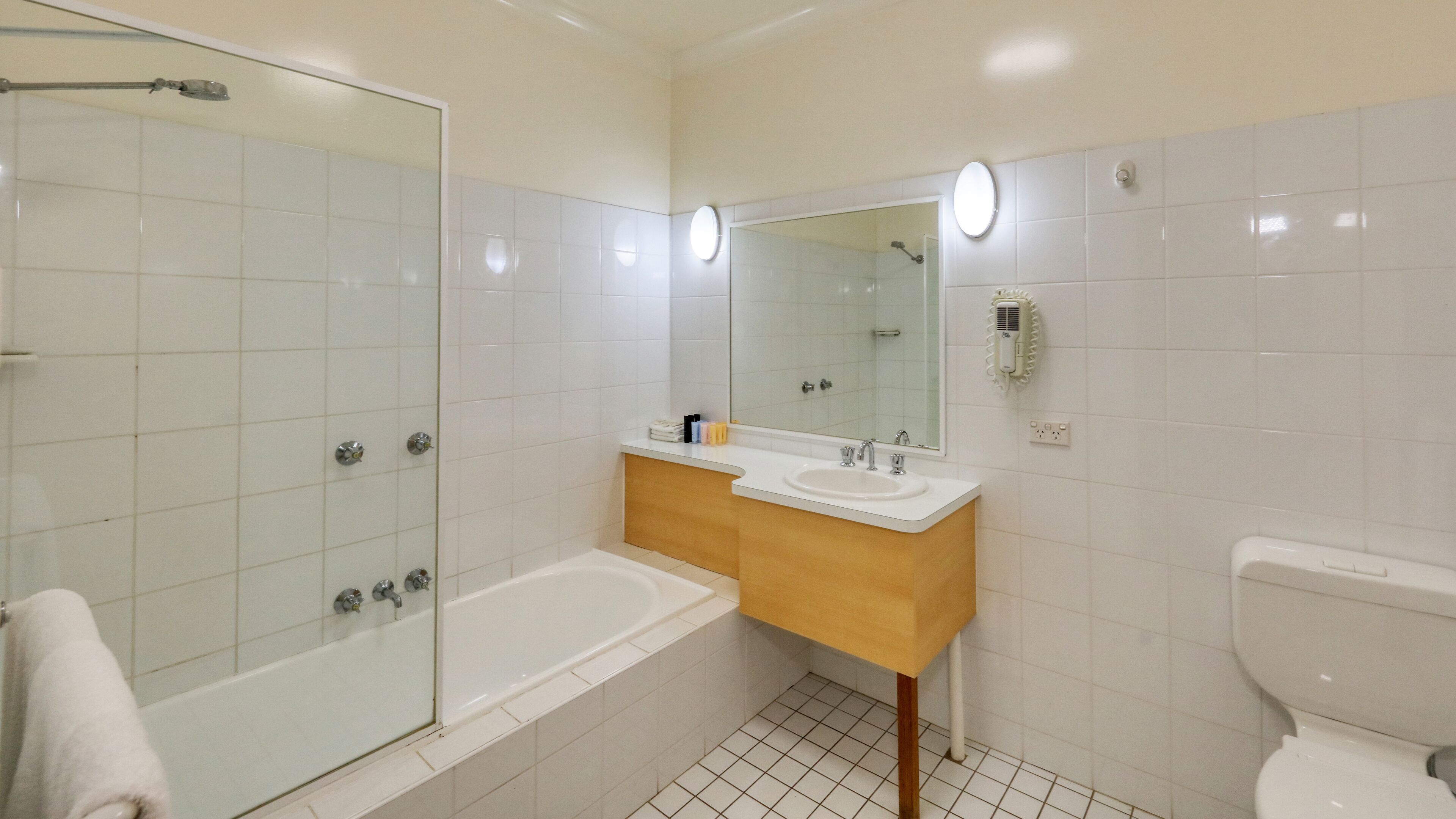 Un baño con ducha vidriada, lavamanos con espejo y retrete.