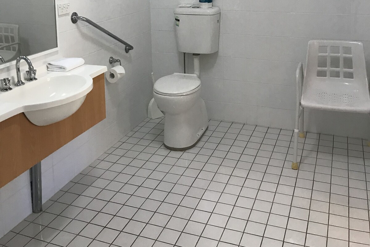 Een badkamer met een wit wastafel, spiegel, toilet en een kleine prullenbak.