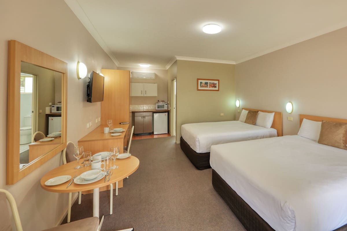 Una habitación de hotel con dos camas, comedor, cocina y baño.