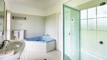 Een badkamer met een bad, een wastafel en een douchecabine van glas.