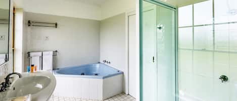 A bathroom with a bathtub, a sink, and a glass shower enclosure.