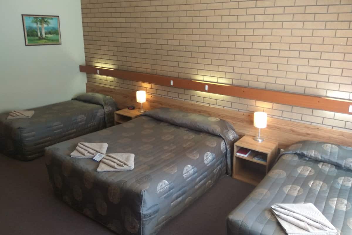 A hotel room with two beds, each with a headboard, a nightstand, and a lamp. There is a framed picture on the wall.
