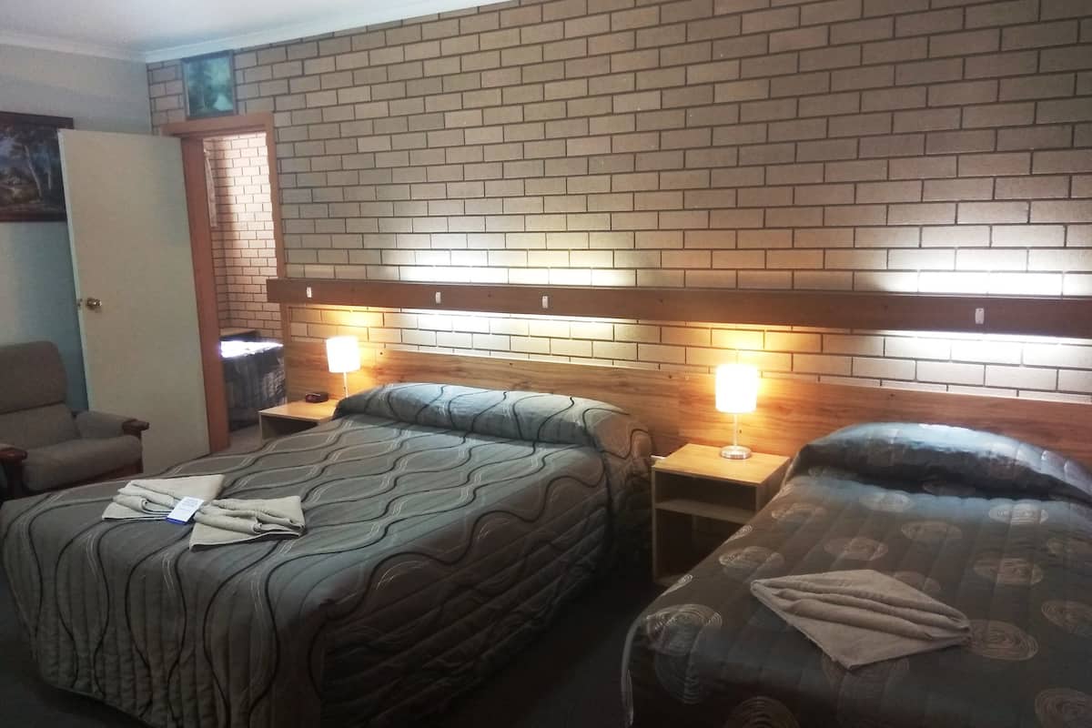 A hotel room with two beds, a brick-patterned headboard, and bedside lamps.