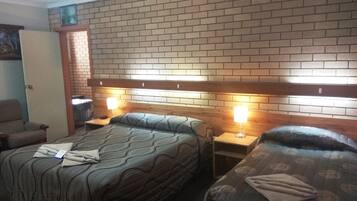 A hotel room with two beds, a brick-patterned headboard, and bedside lamps.