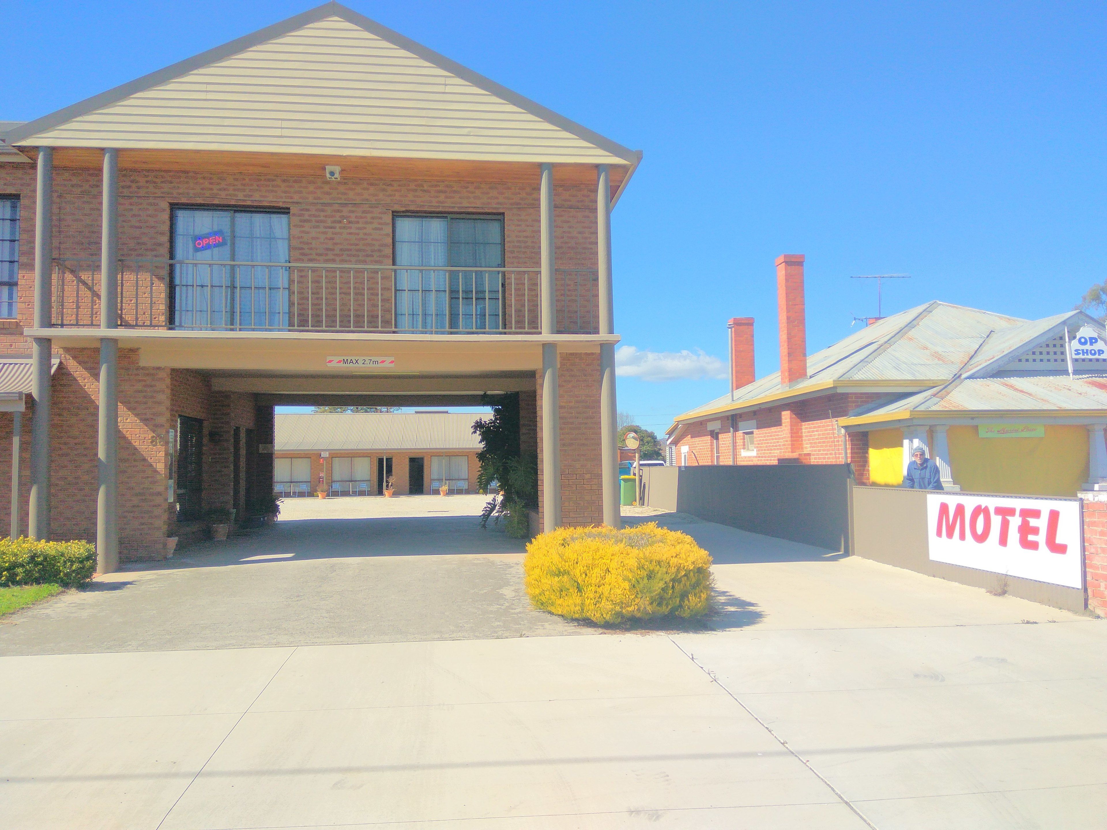 A two-story motel with a flat roof, a covered entrance, and a sign indicating a maximum height clearance of 2.7 meters.