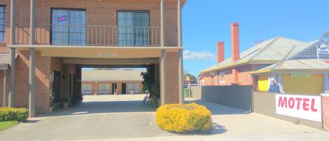 A two-story motel with a flat roof, a covered entrance, and a sign indicating a maximum height clearance of 2.7 meters.