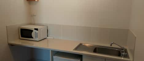 Cocina compacta con microondas, lavabo y refrigerador pequeño.