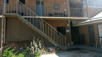 A two-story building with a brick facade, a staircase leading to a balcony, and a sign indicating "Guest Laundry".