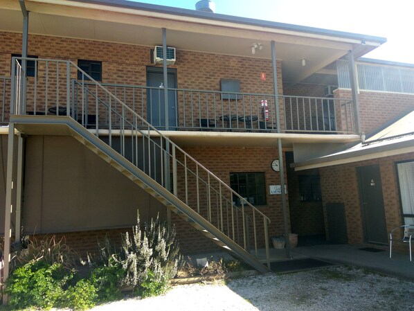 A two-story building with a brick facade, a staircase leading to a balcony, and a sign indicating "Guest Laundry".