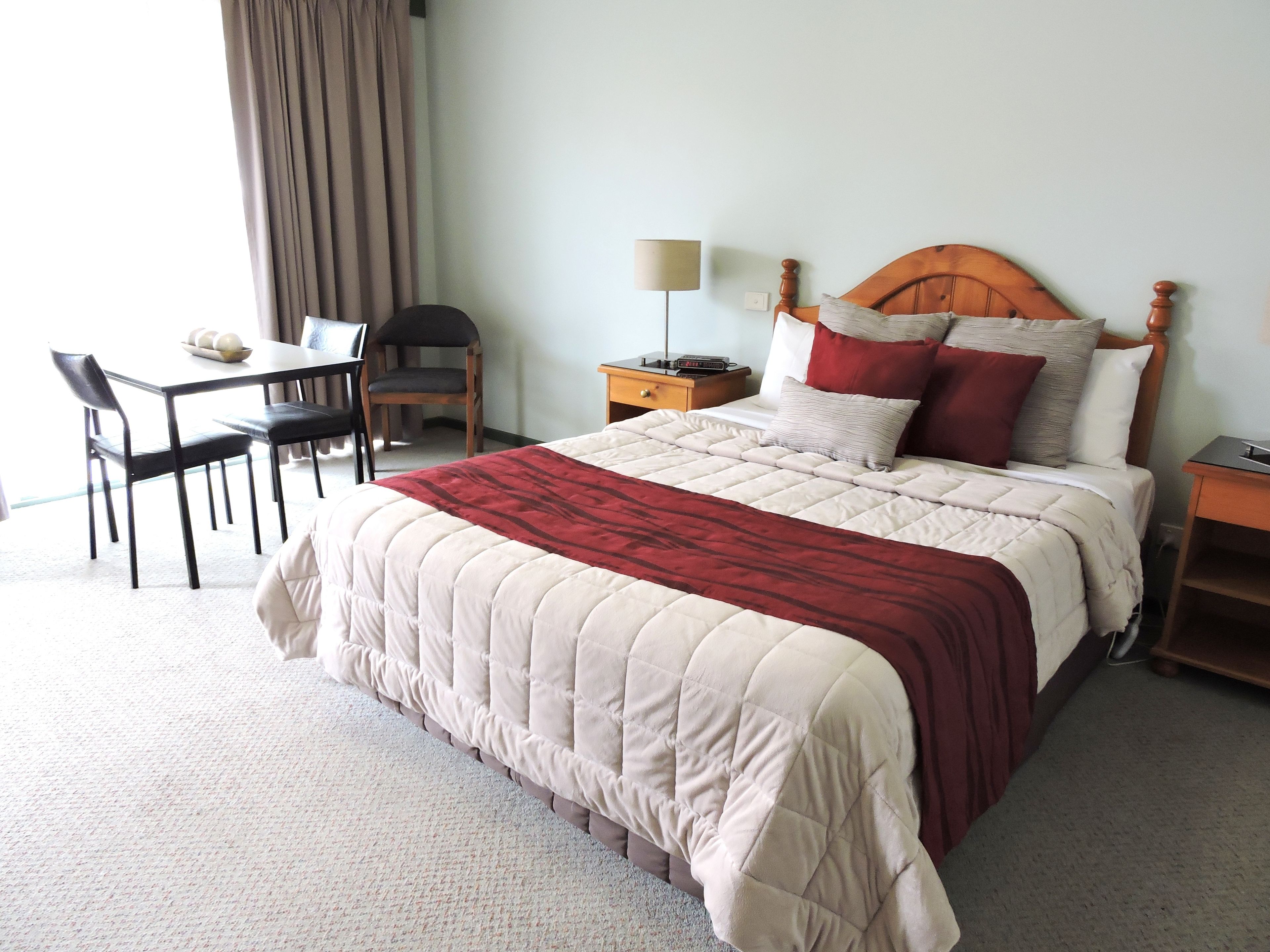 Quarto de hotel com uma cama, uma escrivaninha e uma cadeira.