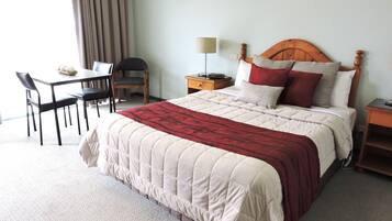 Quarto de hotel com uma cama, uma escrivaninha e uma cadeira.