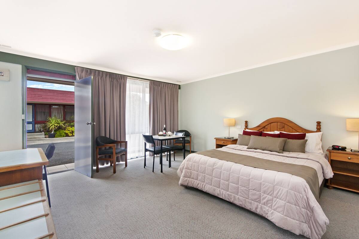A hotel room with a bed, desk, chair, and a view of the outside.