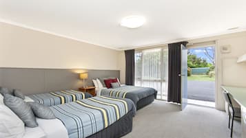 Quarto de hotel com duas camas, uma escrivaninha e vista para o exterior.