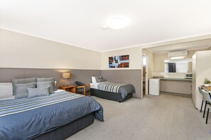 Une chambre d’hôtel avec deux lits, un bureau, un réfrigérateur et une kitchenette.