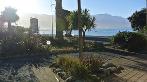 Eine angelegte Grünfläche mit einem Schild für Blue Seas Motels, einem Weg und Blick auf das Meer und die Berge.
