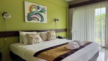 A hotel room with a large bed, green walls, and a painting of a swan.