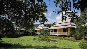 A traditional building with a tiled roof, surrounded by lush greenery and a small pond. - Poonyamantra Resort Chiang Rai (Mae Sai)