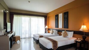 A hotel room with two beds, a desk, a chair, a lamp, and artwork on the walls. - Poonyamantra Resort Chiang Rai (Mae Sai)