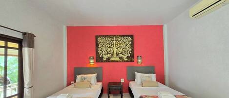 Habitación de hotel con dos camas, una pared de acento roja, un cuadro decorativo de un árbol y un equipo de aire acondicionado.