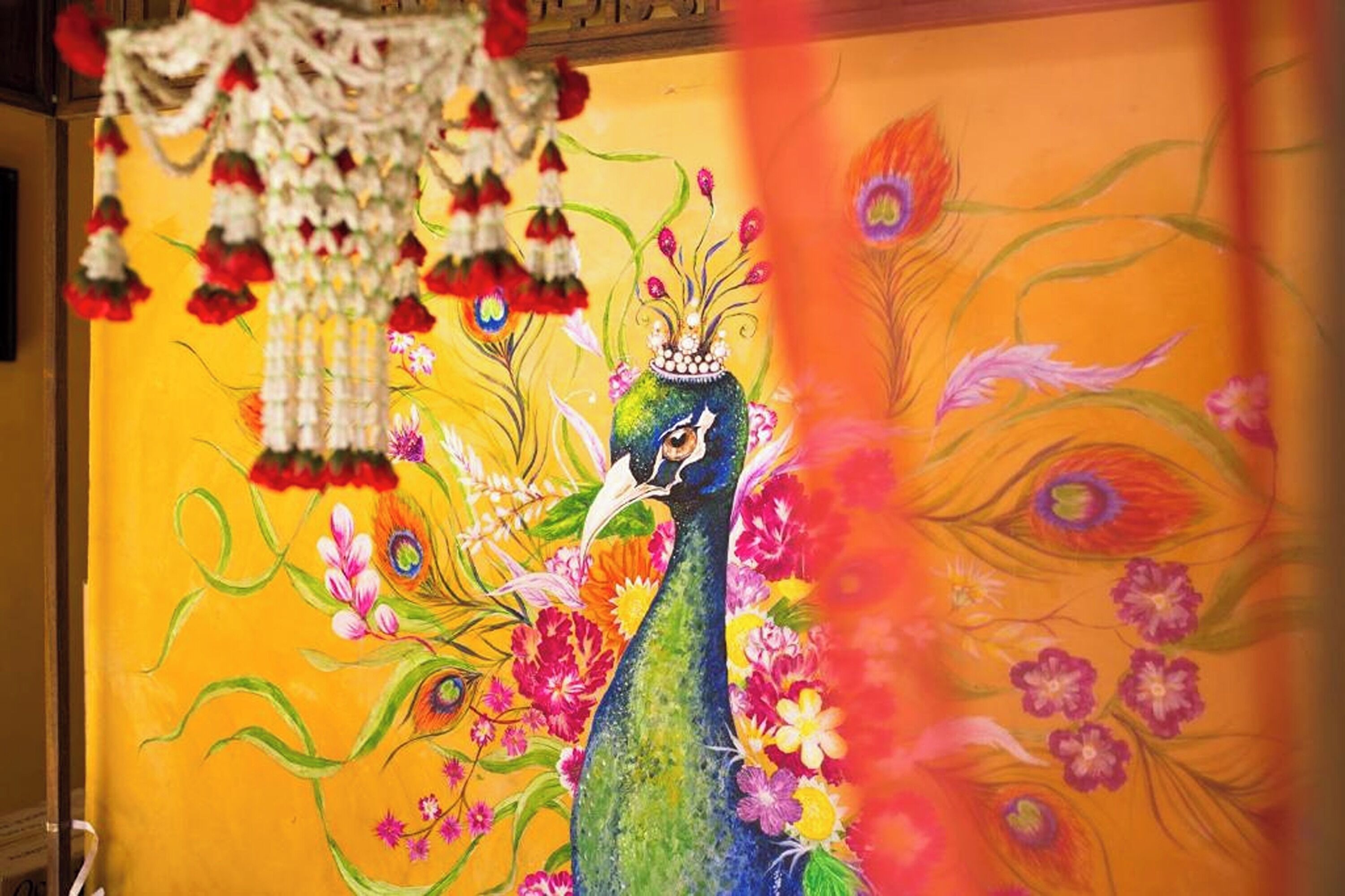 A vibrant peacock mural with floral and eye motifs on a yellow background.