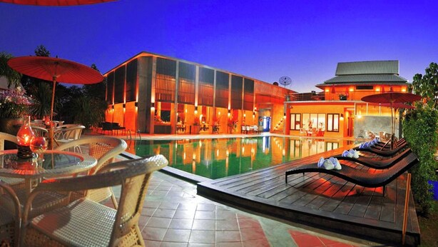 A modern hotel with a swimming pool, outdoor seating, and a well-lit facade. - Poonyamantra Resort Chiang Rai (Mae Sai)